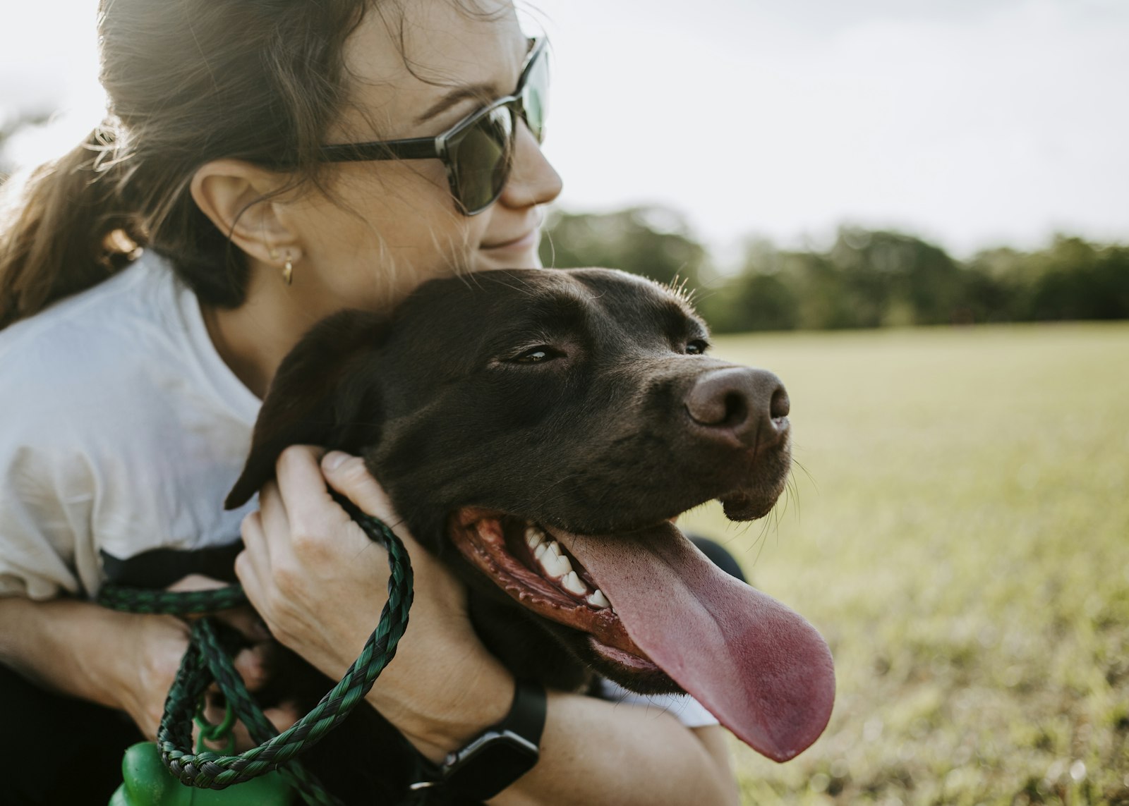 Happy dog owner hugging her dog outdoors